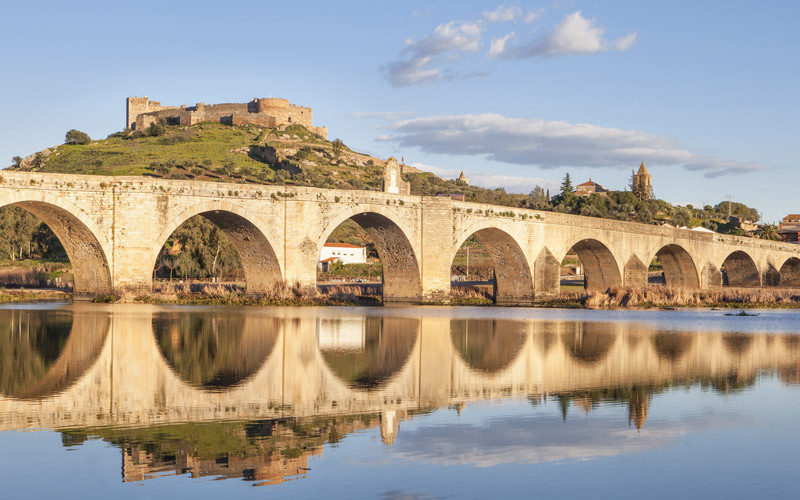 Pont romain reconstruit en 1630, puisque l'original se trouve sous les eaux du Guadiana. En arrière-plan, le château de Medellín en haut de la colline