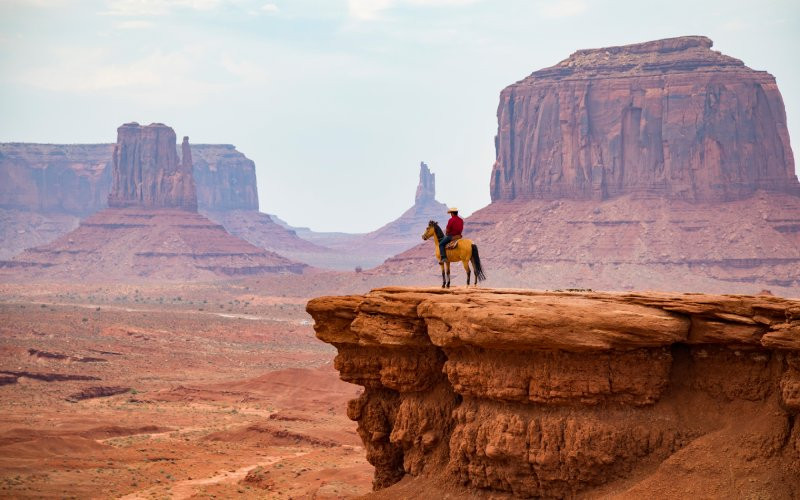 Un cow-boy à cheval dans le parc tribal Navajo à Monument Valley