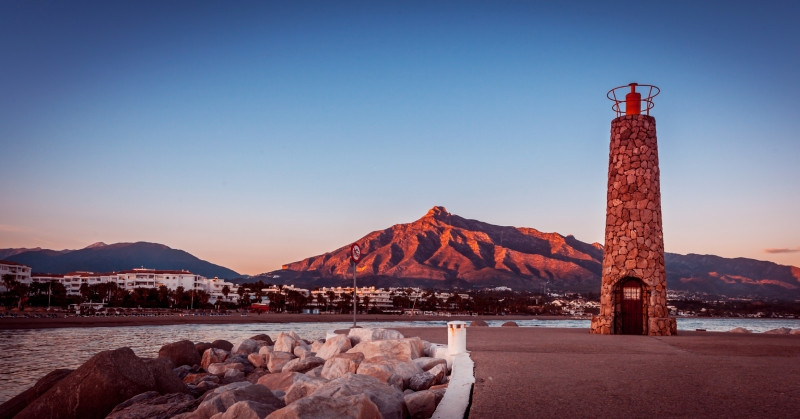 Phare en pierres, montagne derrière au coucher de Soleil