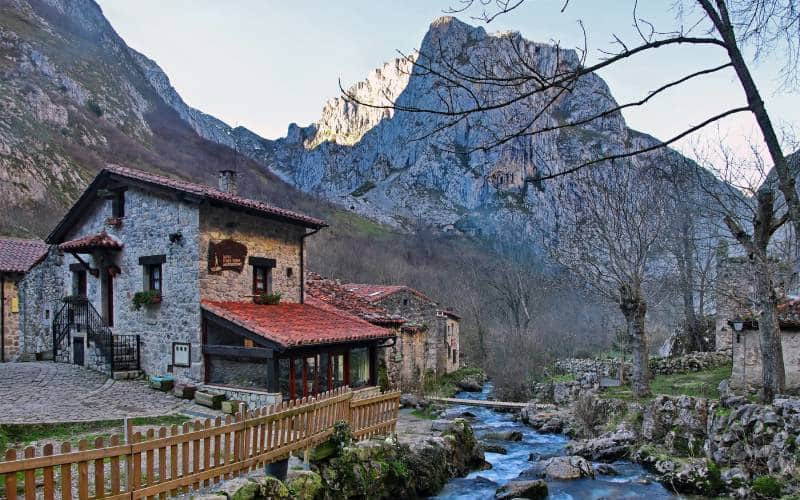 Maison auprès d'une rivière et montagnes derrière