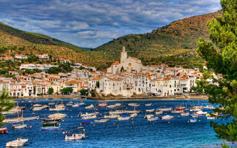 Petits bateaux sur la côte, village aux maisons blanches, collines derrière