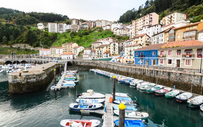 Port, barques amarrées et maisons sur une colline